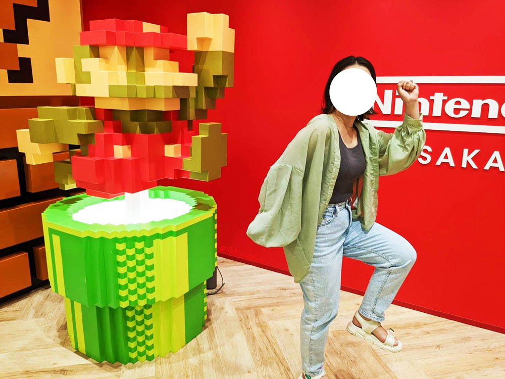 Nintendo OSAKAのフォトスポットで写真撮影。ドット絵のマリオの置物（土管の上でジャンプしている）と、同じボーズを取る私。